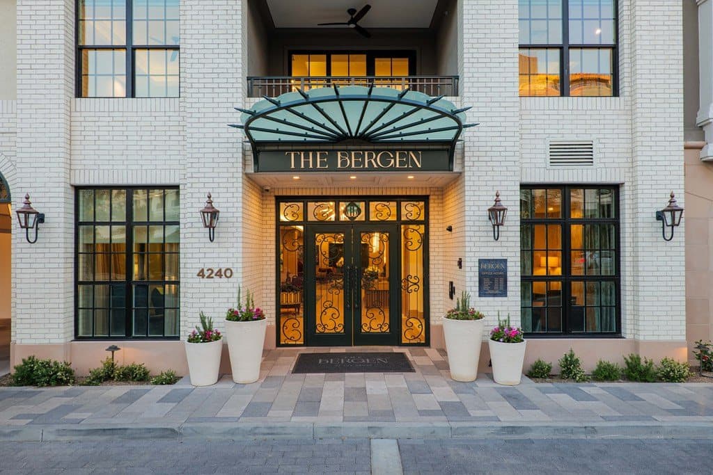 White brick entrance with arched glass canopy and ornamental iron doors